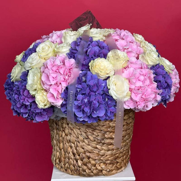 Basket of pink, blue hydrangeas and ivory roses Royal Symphony
